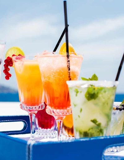 Various fruity drinks served on a blue tray, on the top deck of a yacht.