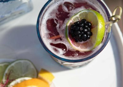 Top view of a mixed blackberry and vodka drink, garnished with a slice of lime and a blackberry.