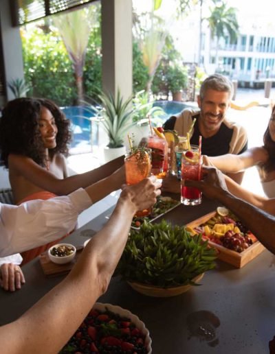 People toasting with different fruity drinks sitting at a table
