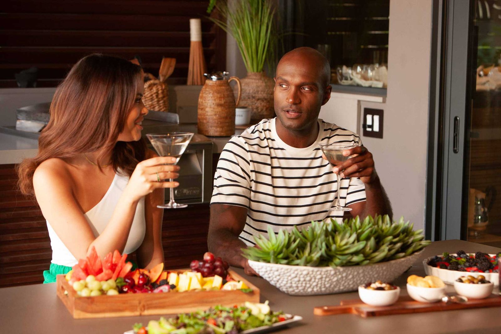 Vodka in two shot glasses behind a cracker with black caviar on it, displayed on a wooden board